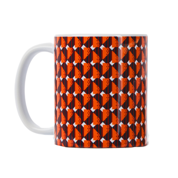 A ceramic mug with a geometric moquette pattern in orange, black, and white colors, resembling the design of old subway car seats.