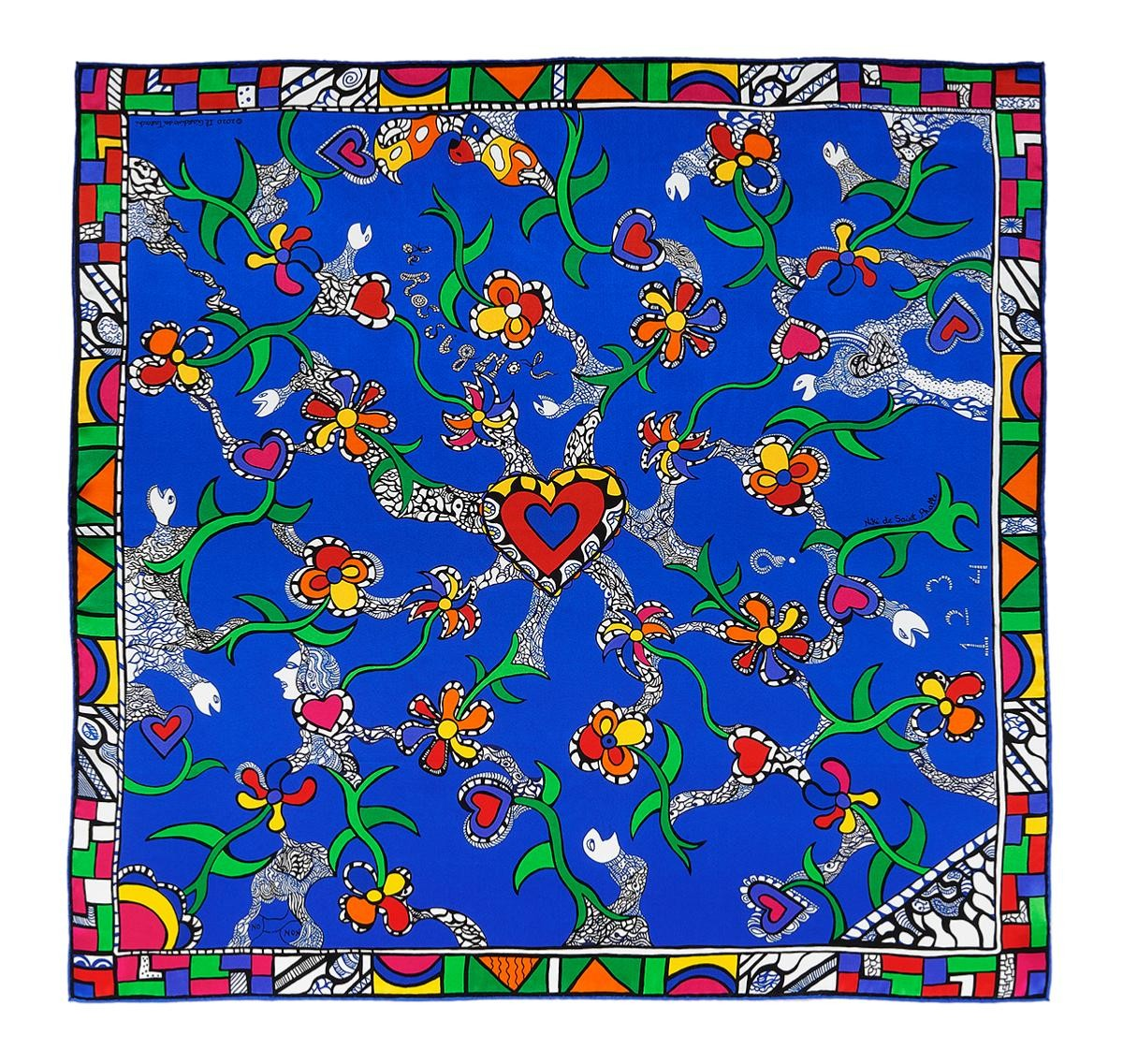 A person wearing a blue silk scarf with a vibrant geometric pattern around their neck.