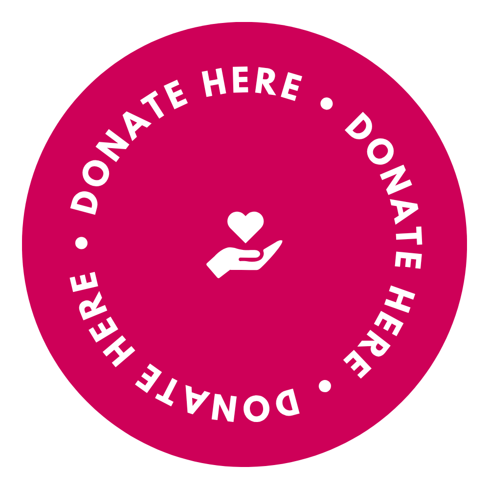 Pink circular sticker with 'Donate Here' text and a hand holding a heart icon on a white background