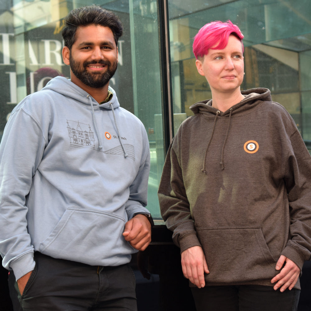 Two people wearing branded hoodies standing indoors with a glass ceiling.