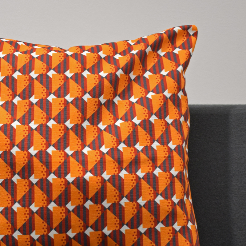 A close up shot of cushion cover with a geometric moquette pattern in orange and gray, displaying a piece of Glasgow's transport history.