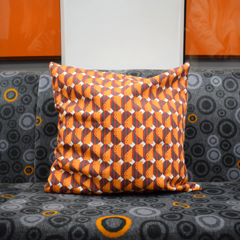 A cushion cover with a geometric moquette pattern in orange and gray, displaying a piece of Glasgow's transport history.