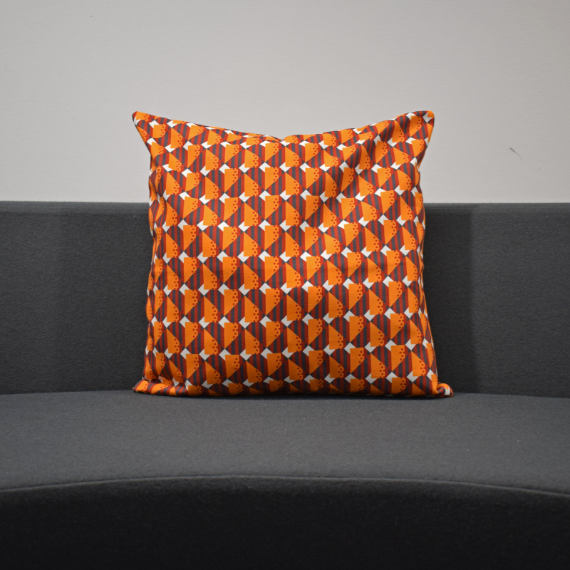 A cushion cover with a geometric moquette pattern in orange and gray, displaying a piece of Glasgow's transport history.