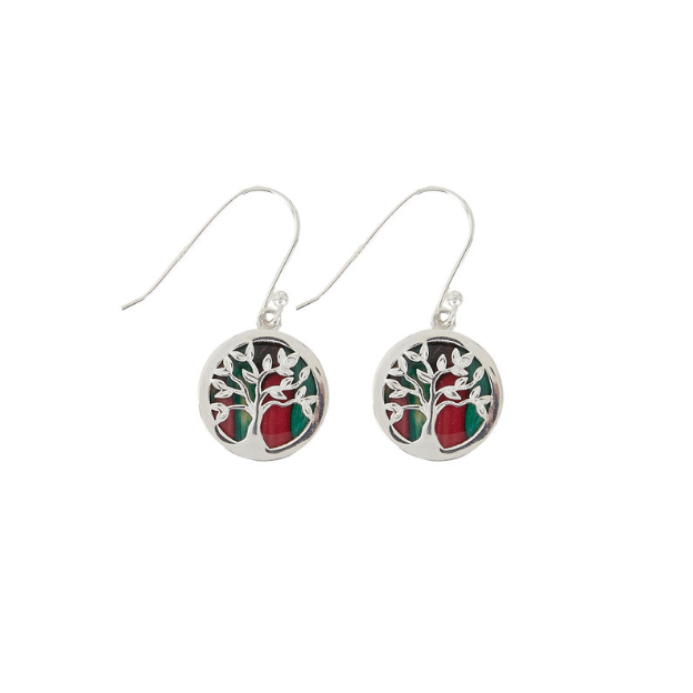 A pair of silver earrings featuring a circular design with a tree motif in the center, surrounded by a red and green pattern, suspended from fish hooks.