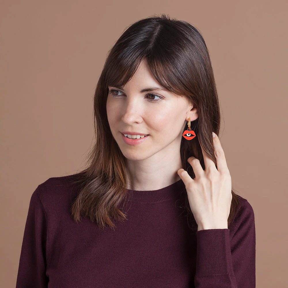 Woman wearing red earrings against a brown background