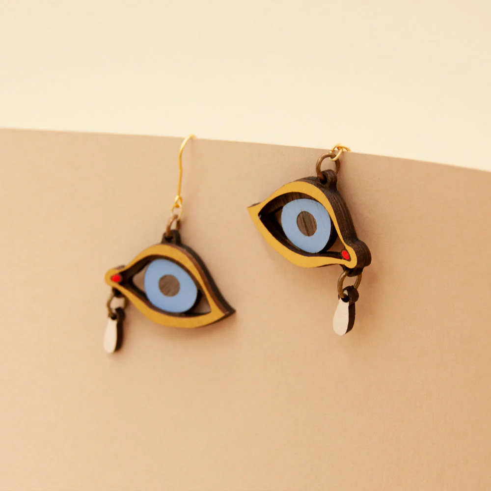Eye-shaped earrings on a beige background
