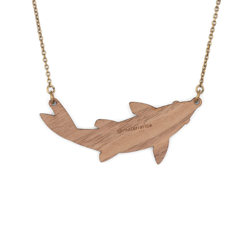 Wooden shark-shaped pendant on a chain with 'materiarte' branding.